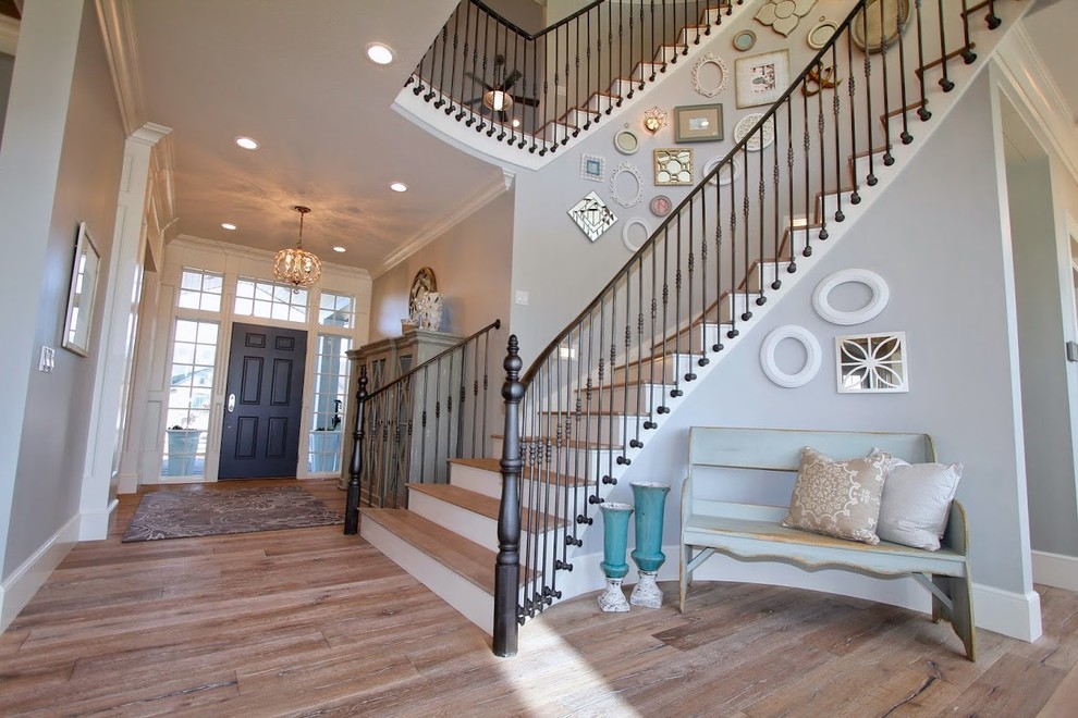 Example of a huge country wooden curved staircase design in Salt Lake City with wooden risers