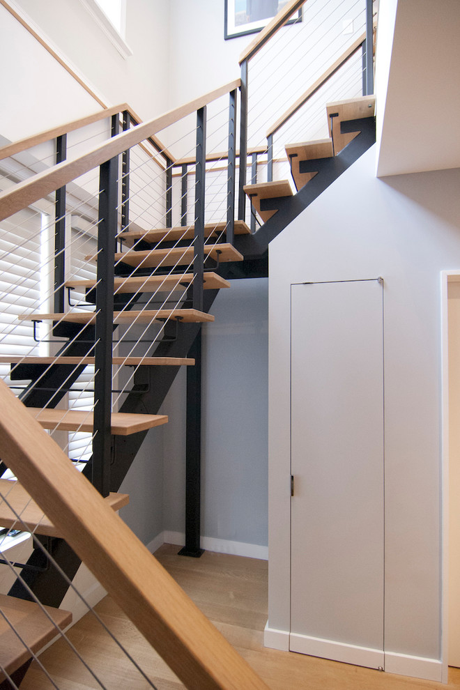 Idée de décoration pour un grand escalier sans contremarche design en U avec des marches en bois et un garde-corps en câble.