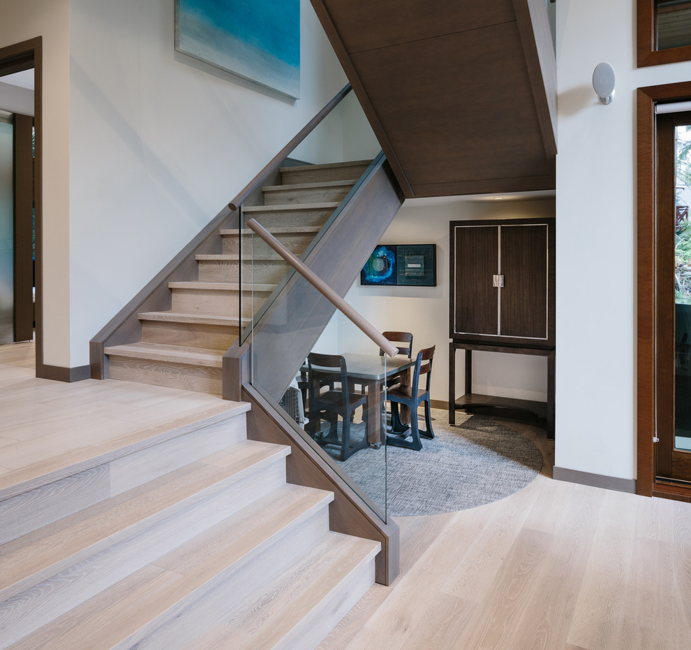 Photo of a large contemporary wood u-shaped glass railing staircase in Vancouver with wood risers.