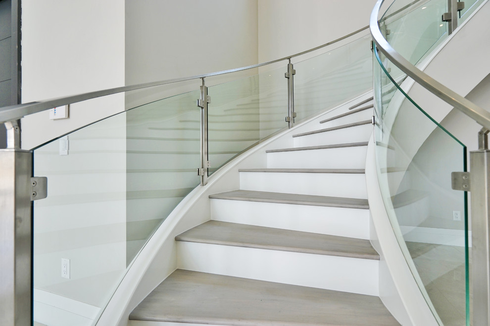 На фото: изогнутая лестница среднего размера в стиле модернизм с деревянными ступенями, крашенными деревянными подступенками и стеклянными перилами с