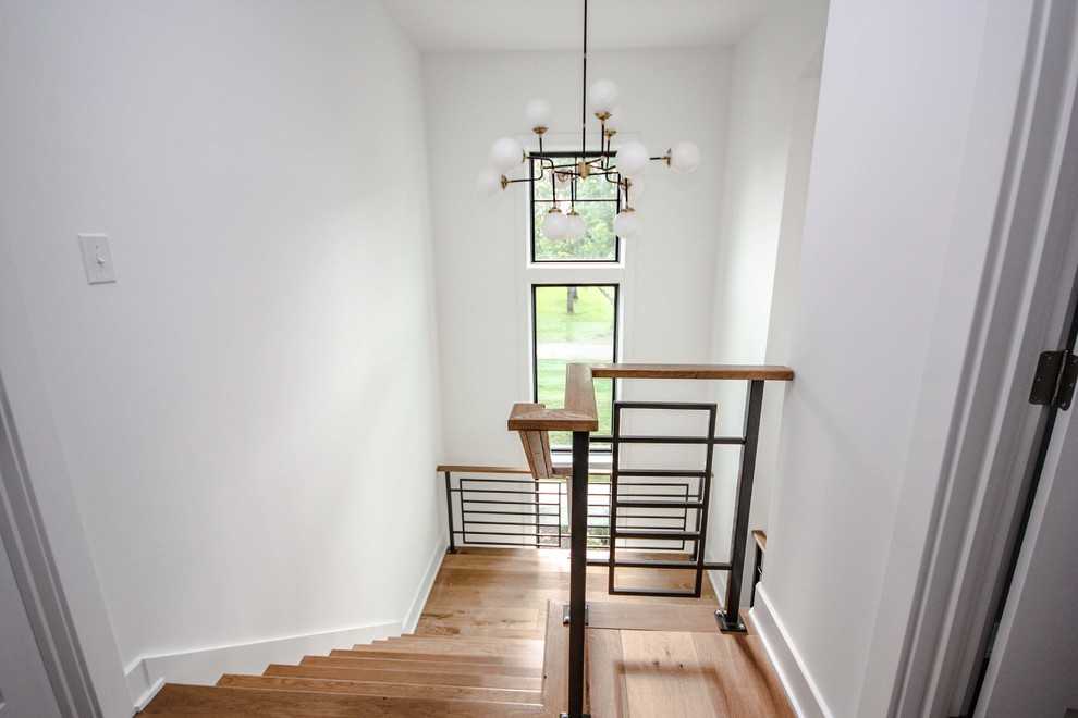 Modelo de escalera en U de estilo de casa de campo de tamaño medio con escalones de madera, contrahuellas de madera pintada y barandilla de metal