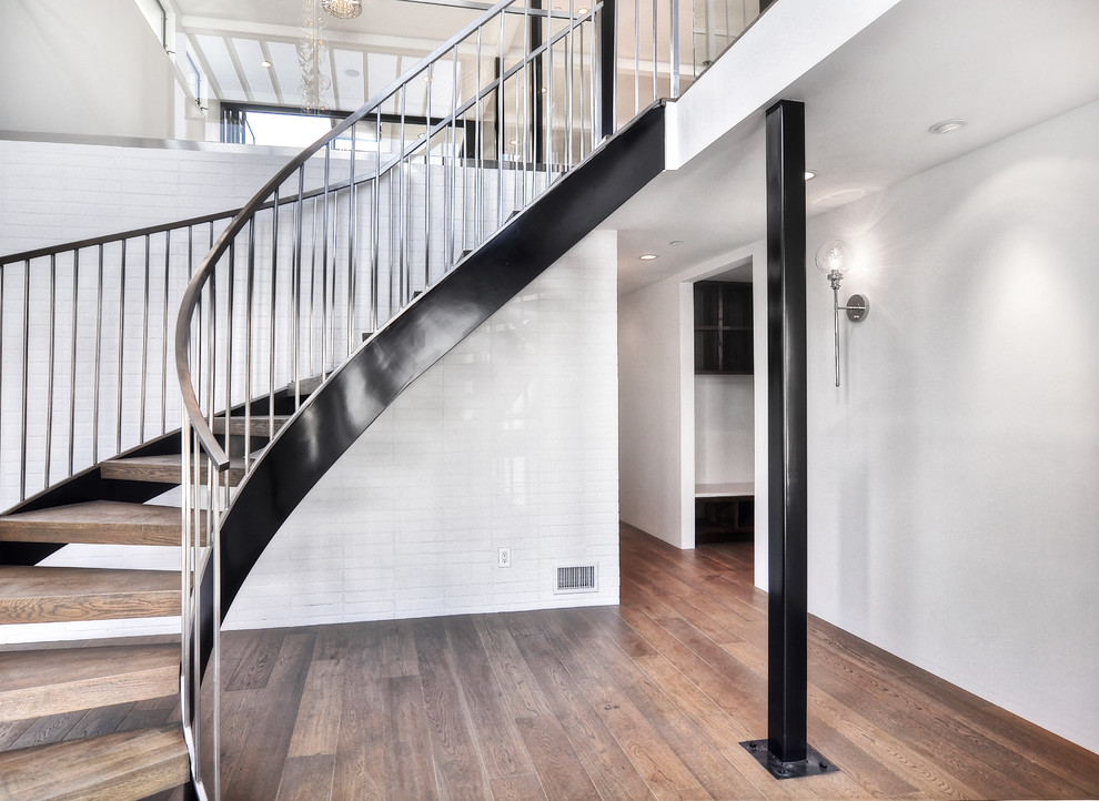 Imagen de escalera curva actual de tamaño medio sin contrahuella con escalones de madera y barandilla de metal