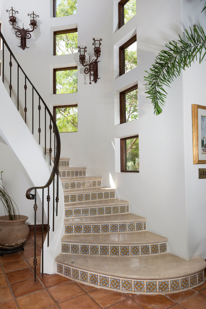 Пример оригинального дизайна: изогнутая лестница среднего размера в средиземноморском стиле с подступенками из плитки
