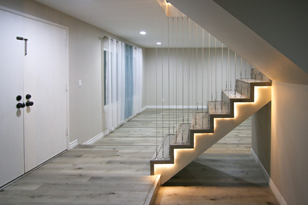 Imagen de escalera en U moderna de tamaño medio con escalones de madera, contrahuellas de madera y barandilla de cable