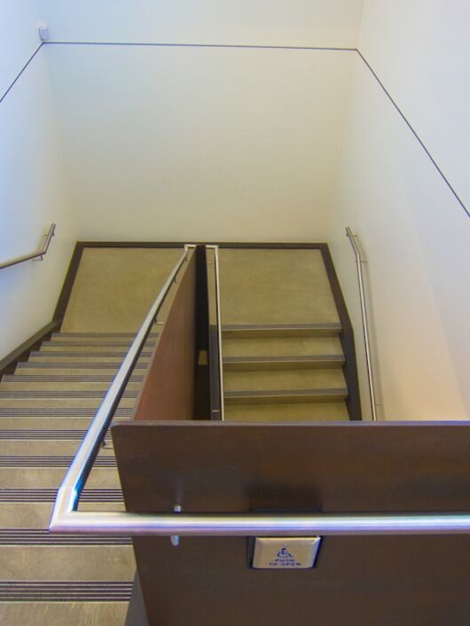 Réalisation d'un grand escalier design en U et béton avec des contremarches en métal.
