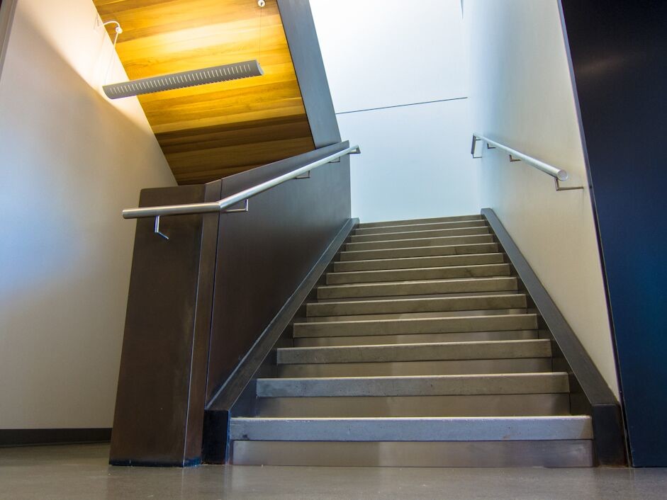Diseño de escalera en U actual grande con escalones de hormigón y contrahuellas de metal
