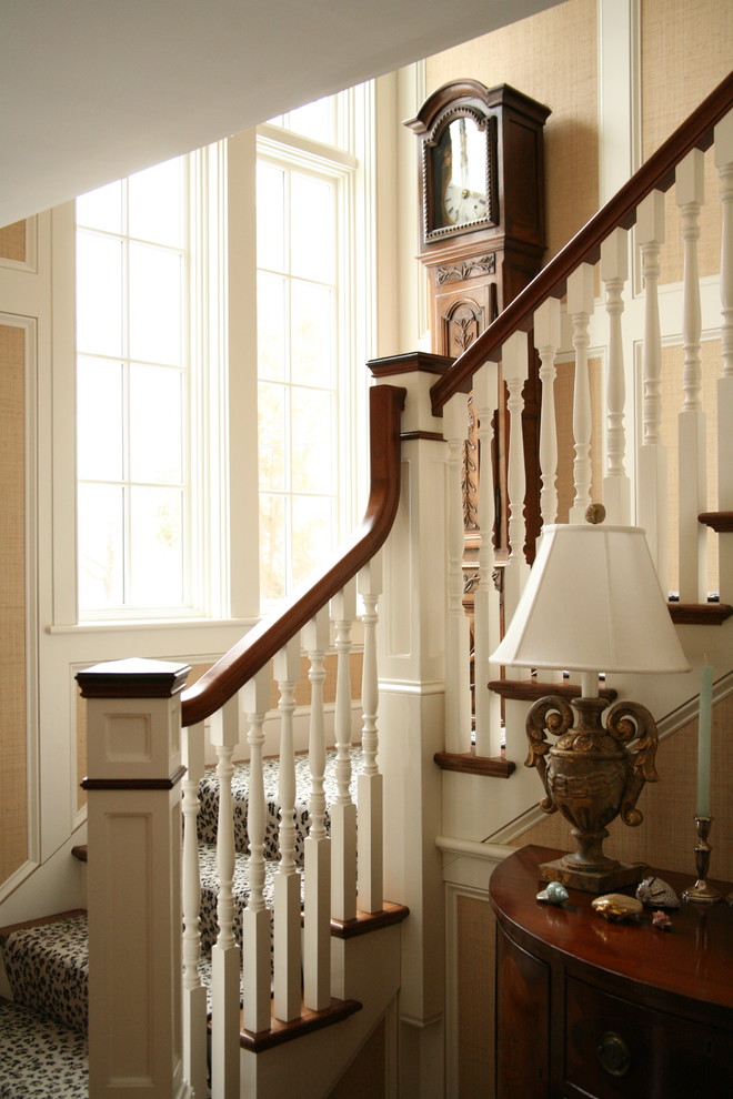 Пример оригинального дизайна: большая угловая лестница в викторианском стиле с деревянными ступенями и крашенными деревянными подступенками