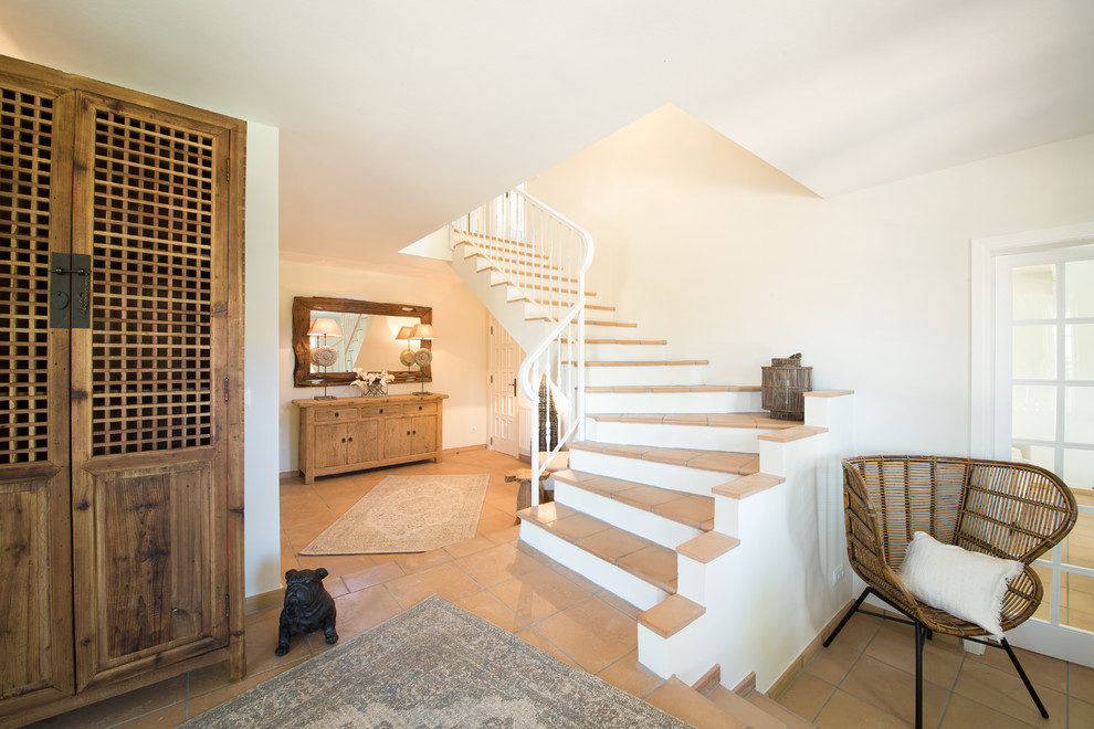 На фото: угловая бетонная лестница среднего размера в средиземноморском стиле с ступенями из терракотовой плитки с