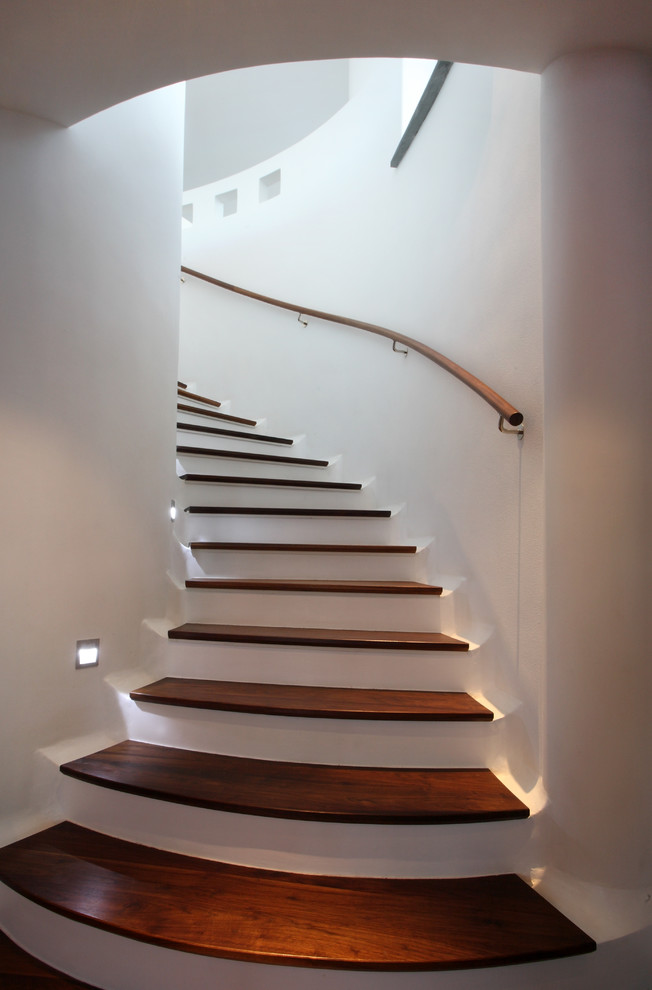 На фото: изогнутая бетонная лестница среднего размера в современном стиле с деревянными ступенями с