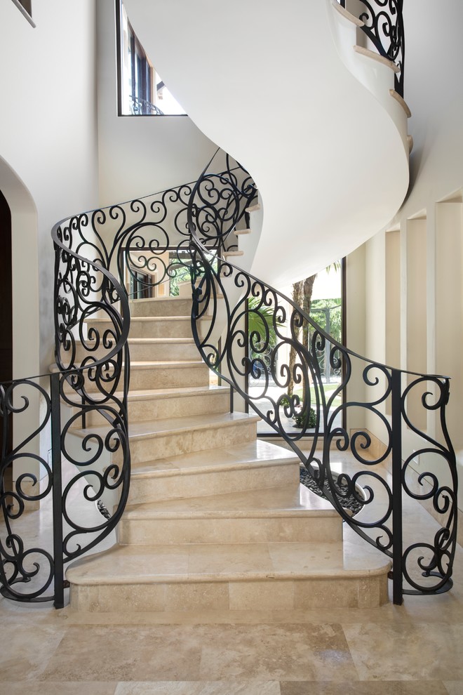 На фото: огромная винтовая лестница в средиземноморском стиле с ступенями из плитки и подступенками из плитки с