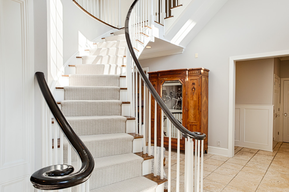 Huge elegant carpeted curved wood railing staircase photo in Philadelphia with carpeted risers
