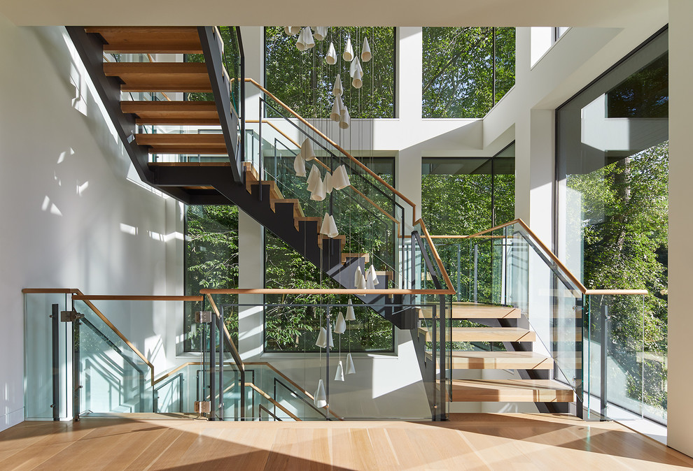 На фото: огромная угловая лестница в современном стиле с деревянными ступенями и перилами из смешанных материалов без подступенок