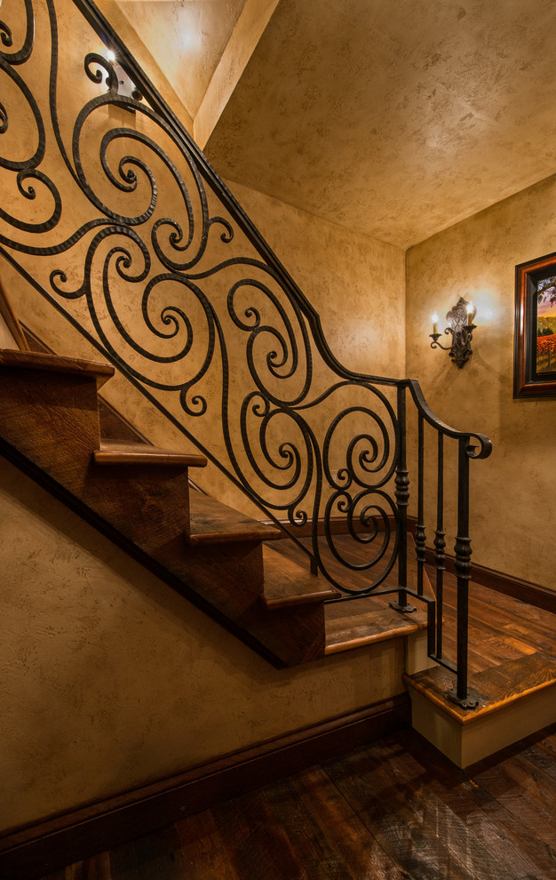 На фото: большая угловая деревянная лестница в классическом стиле с деревянными ступенями и металлическими перилами с