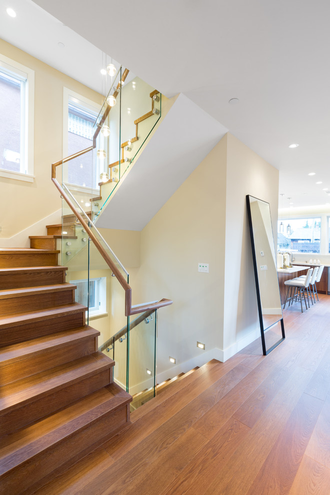 Imagen de escalera en U actual con escalones de madera, contrahuellas de madera y barandilla de vidrio