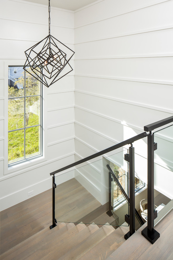 На фото: угловая деревянная лестница среднего размера в современном стиле с деревянными ступенями и стеклянными перилами с
