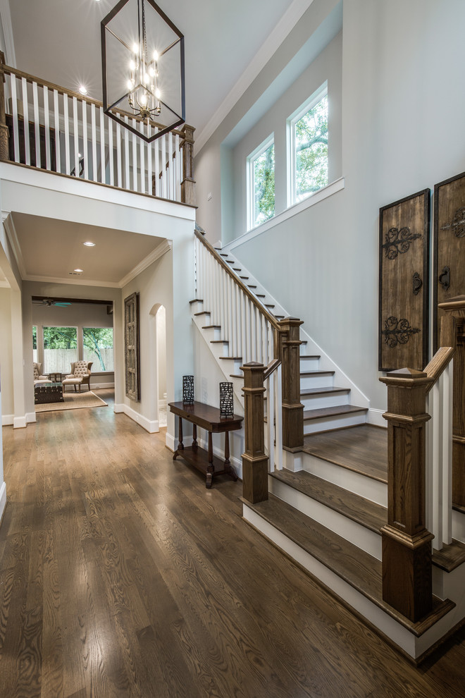 Large classic wood l-shaped wood railing staircase in Houston with painted wood risers.