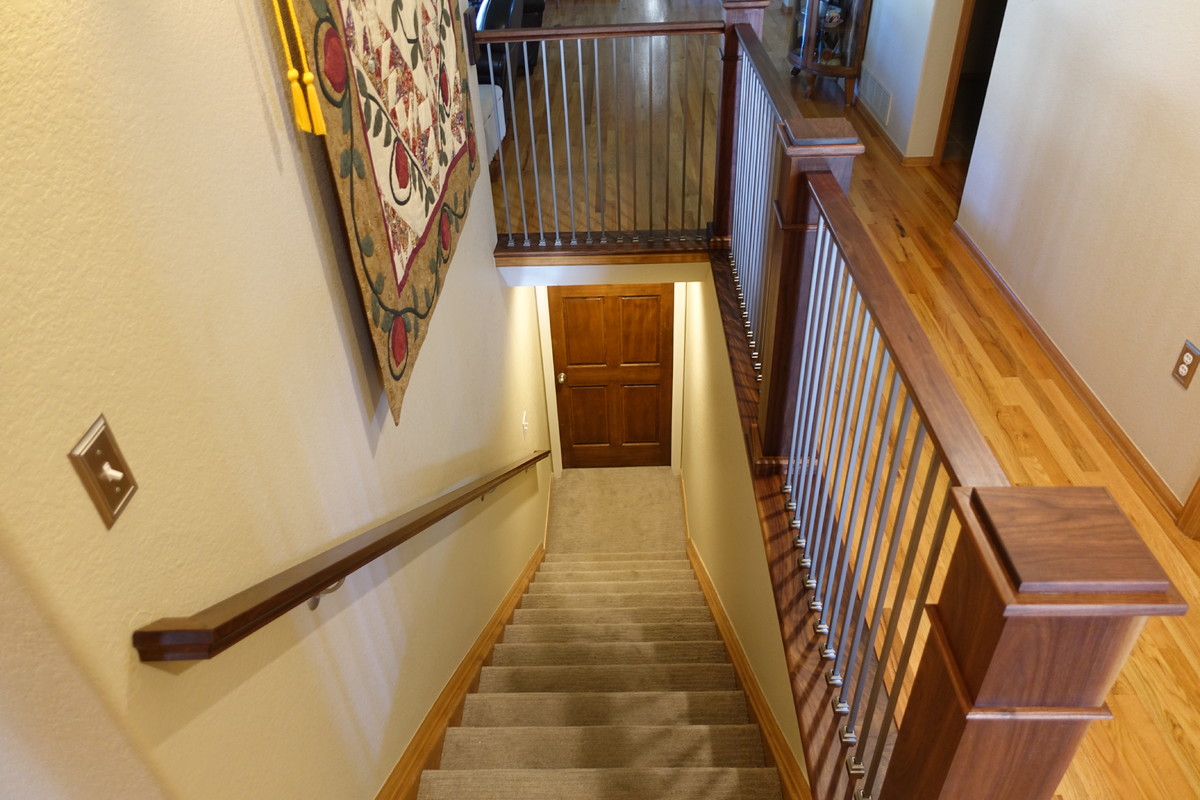 Aménagement d'un petit escalier classique en L avec des marches en moquette, des contremarches en moquette et un garde-corps en bois.