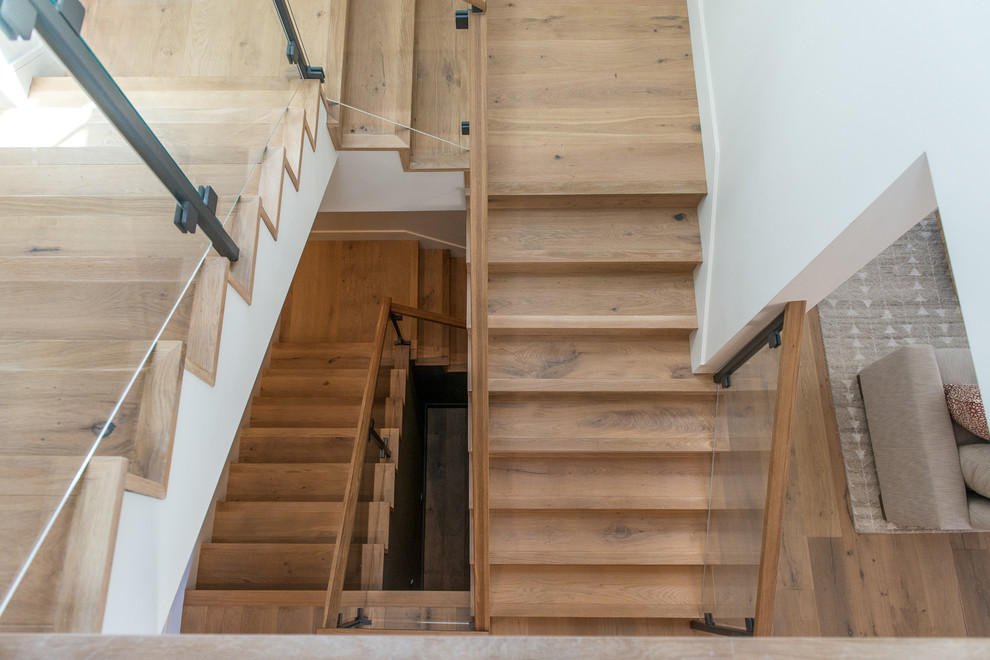 Cette image montre un grand escalier traditionnel en U avec des marches en bois, des contremarches en bois et un garde-corps en matériaux mixtes.
