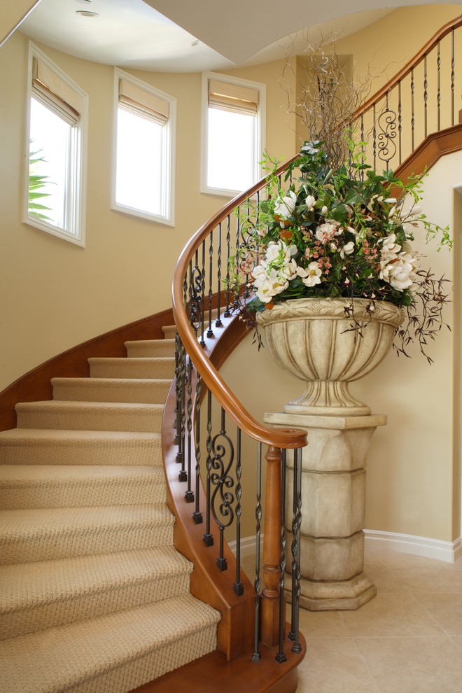 Inspiration for a large coastal carpeted curved wood railing staircase remodel in Orange County with carpeted risers