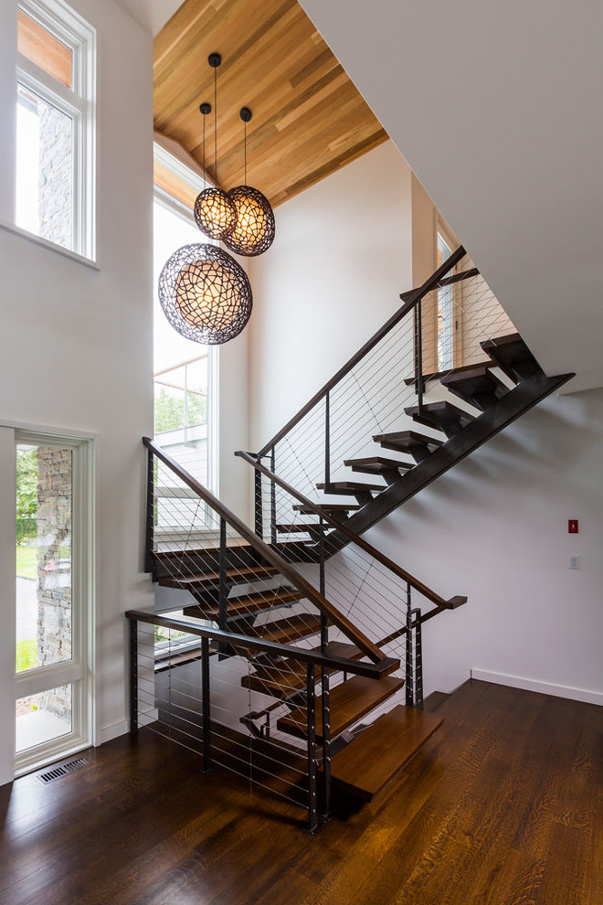 Imagen de escalera en U contemporánea con escalones de madera, contrahuellas de metal y barandilla de cable