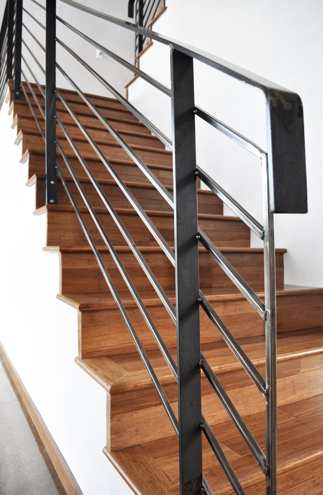 Réalisation d'un grand escalier design en U avec des marches en bois et des contremarches en bois.