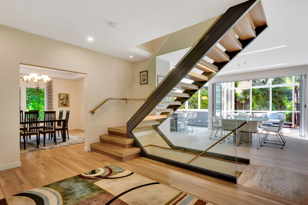 Cette image montre un escalier sans contremarche design en L avec des marches en bois et un garde-corps en verre.