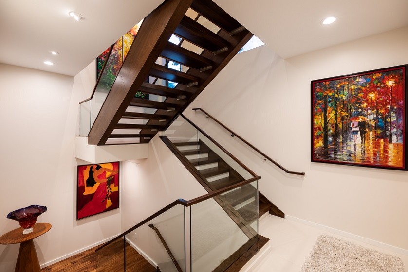 Стильный дизайн: большая п-образная лестница в стиле модернизм с деревянными ступенями и стеклянными перилами без подступенок - последний тренд