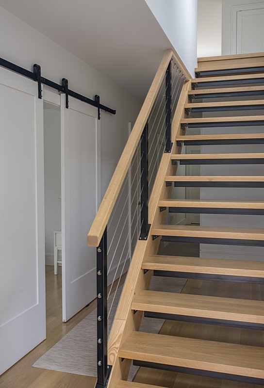 Cette photo montre un escalier sans contremarche droit moderne de taille moyenne avec des marches en bois et un garde-corps en métal.