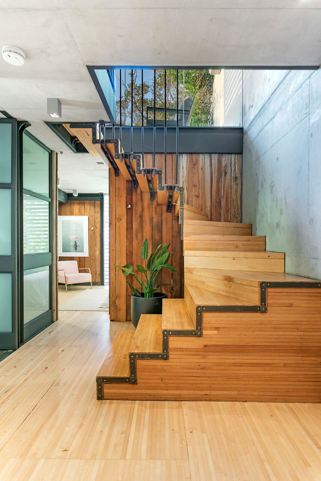 Cette photo montre un escalier industriel en U avec des marches en bois, des contremarches en bois et éclairage.