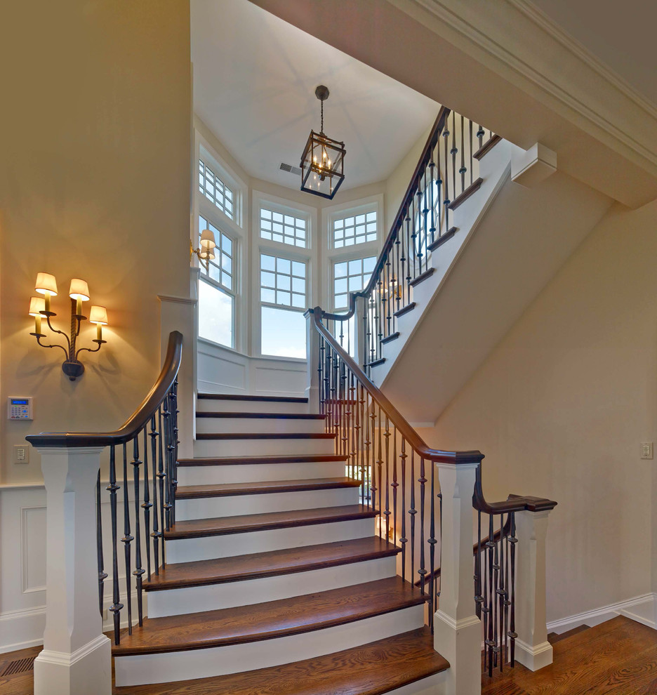Пример оригинального дизайна: большая п-образная лестница в классическом стиле с деревянными ступенями, крашенными деревянными подступенками и перилами из смешанных материалов