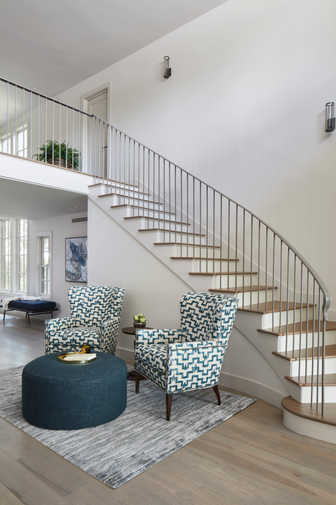 Свежая идея для дизайна: изогнутая лестница в стиле неоклассика (современная классика) с деревянными ступенями, металлическими перилами и крашенными деревянными подступенками - отличное фото интерьера