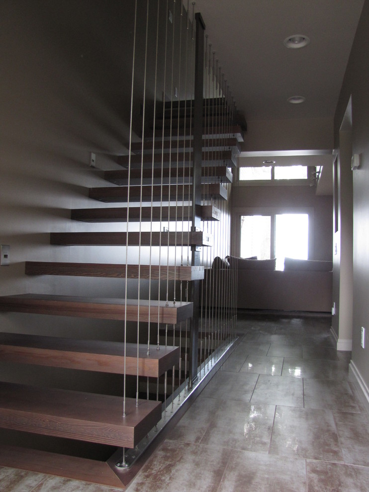 Cette image montre un grand escalier droit minimaliste avec des marches en bois et des contremarches en métal.