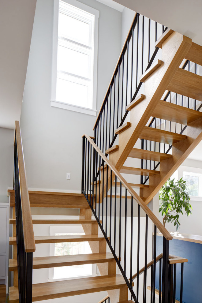 На фото: большая п-образная лестница в стиле кантри с деревянными ступенями и перилами из смешанных материалов без подступенок