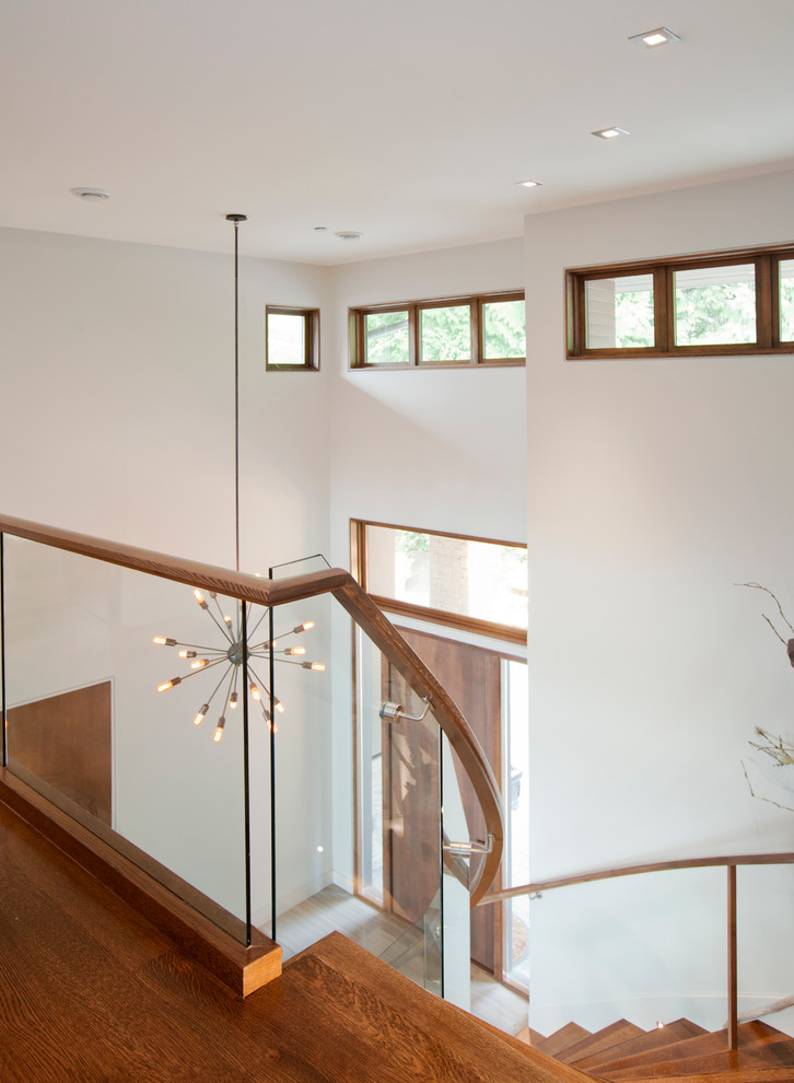 Идея дизайна: большая изогнутая деревянная лестница в современном стиле с деревянными ступенями и деревянными перилами