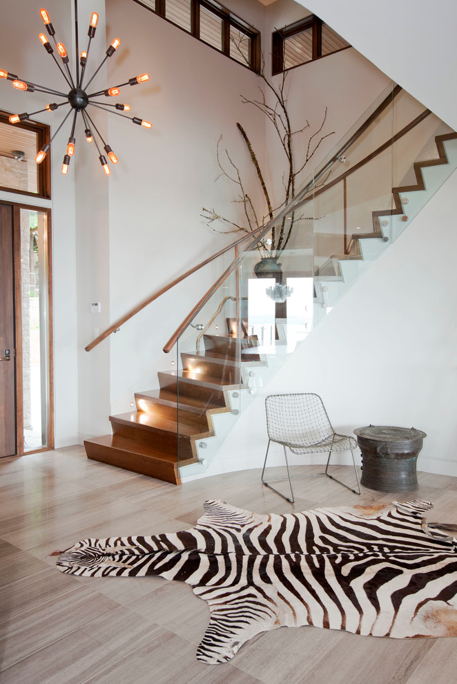 Imagen de escalera curva contemporánea con escalones de madera, contrahuellas de madera y barandilla de vidrio