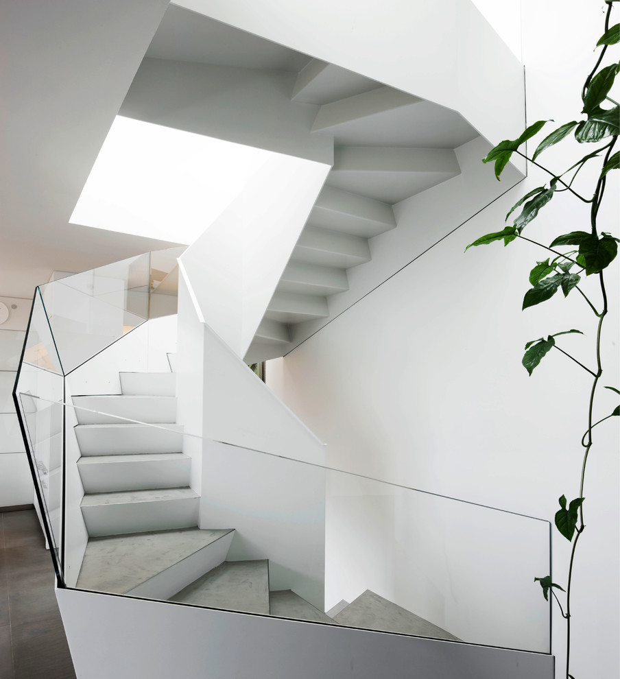 Aménagement d'un grand escalier hélicoïdal moderne avec des marches en métal et un garde-corps en verre.