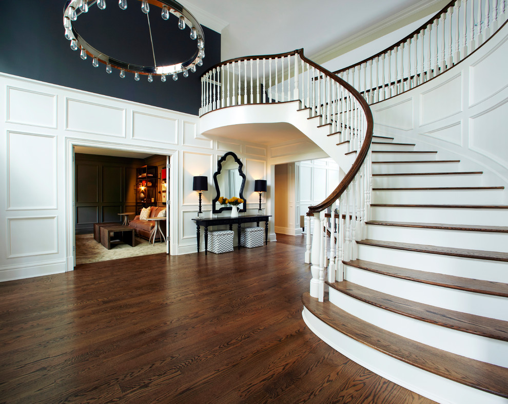 Свежая идея для дизайна: изогнутая лестница в стиле неоклассика (современная классика) с деревянными ступенями - отличное фото интерьера
