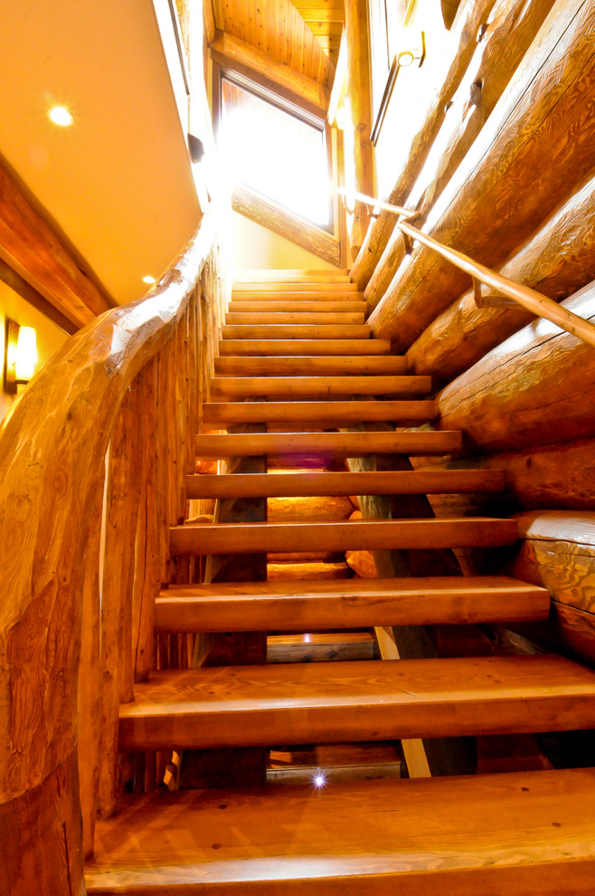 Imagen de escalera recta rústica de tamaño medio con escalones de madera y barandilla de madera