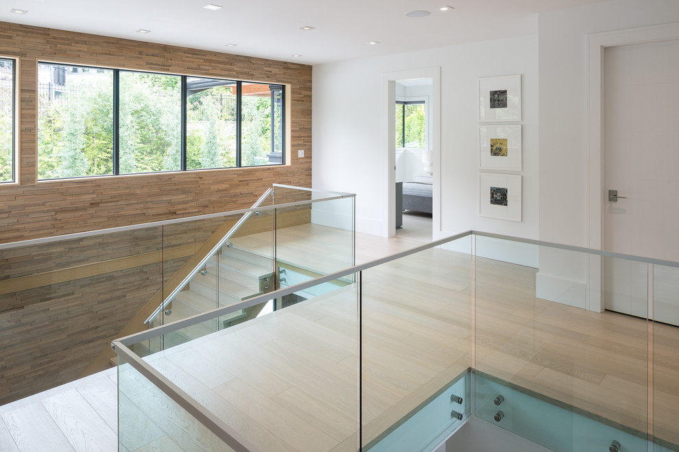 Cette image montre un grand escalier design avec des marches en bois, des contremarches en bois et un garde-corps en verre.