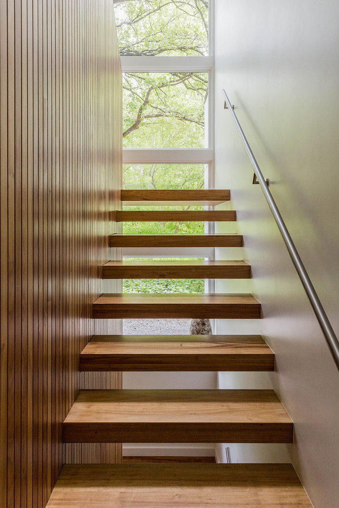 Foto på en mellanstor funkis flytande trappa i trä, med öppna sättsteg och räcke i metall