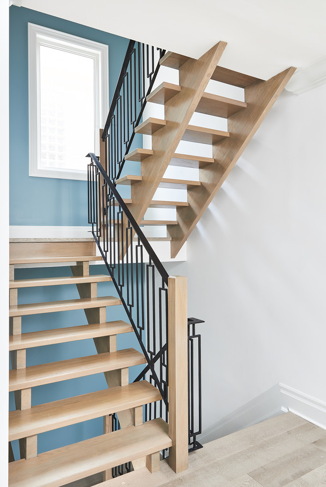 Ejemplo de escalera suspendida de estilo de casa de campo grande con escalones de madera y barandilla de metal