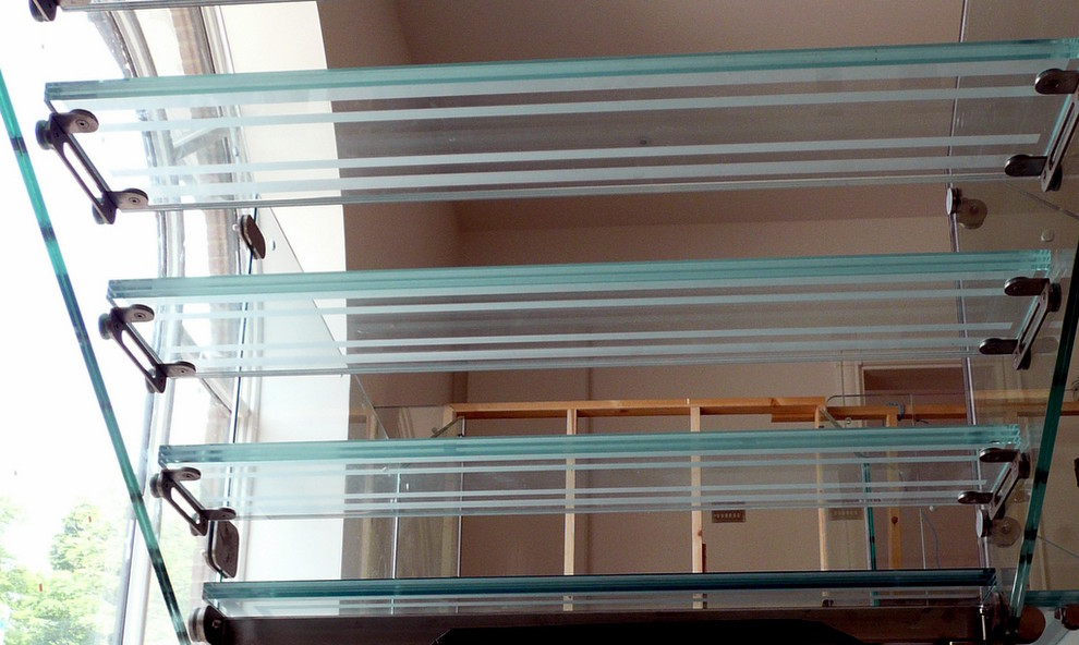 Réalisation d'un très grand escalier flottant design avec des marches en verre, des contremarches en verre et un garde-corps en verre.