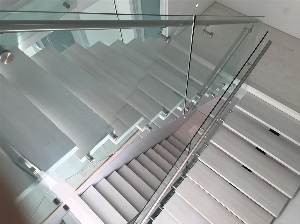 На фото: п-образная лестница среднего размера в стиле модернизм с ступенями из известняка без подступенок с