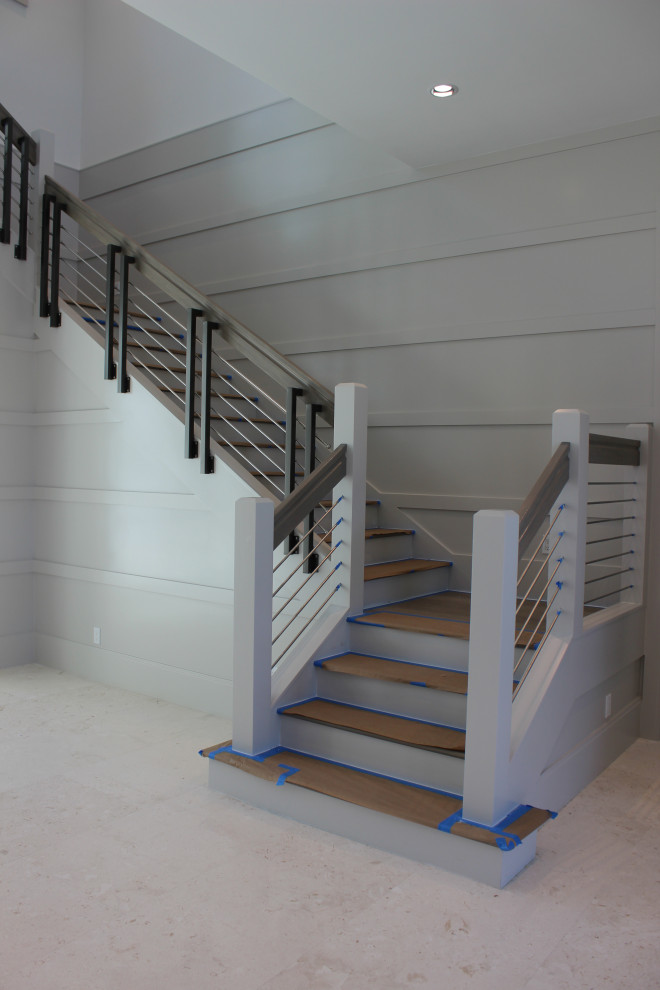Стильный дизайн: большая угловая деревянная лестница в стиле неоклассика (современная классика) с деревянными ступенями, перилами из смешанных материалов и деревянными стенами - последний тренд