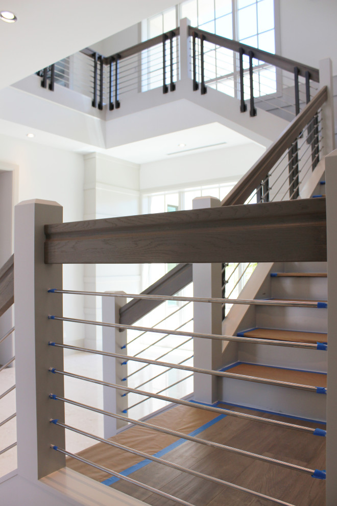 Пример оригинального дизайна: большая угловая деревянная лестница в стиле неоклассика (современная классика) с деревянными ступенями, перилами из смешанных материалов и деревянными стенами