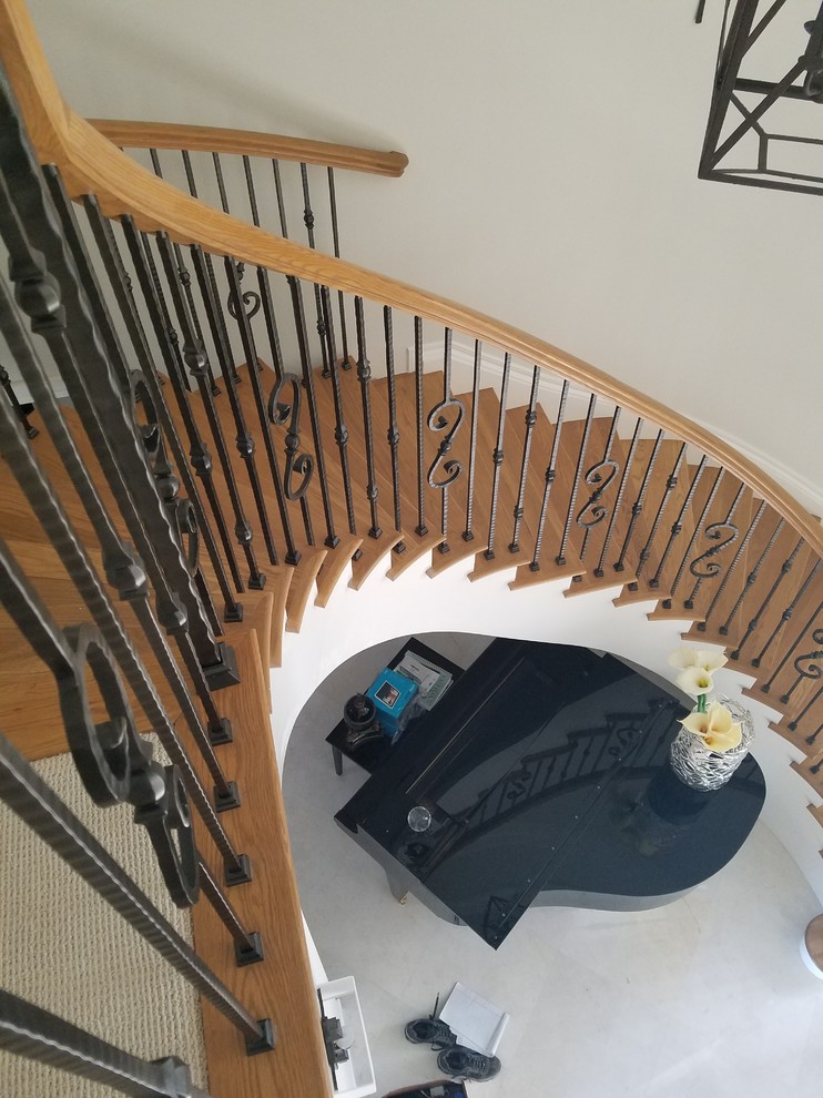 Foto de escalera curva clásica renovada de tamaño medio con escalones de madera, contrahuellas de madera y barandilla de varios materiales