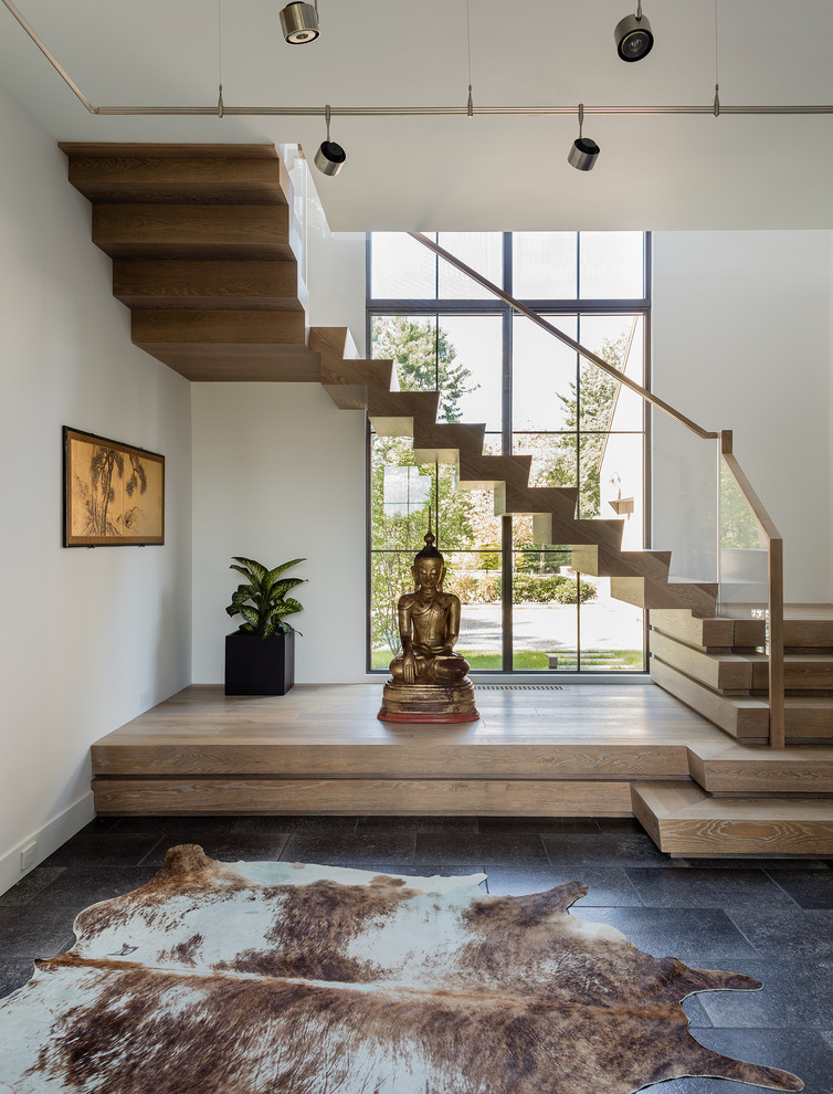 Cette photo montre un escalier tendance en U avec des marches en bois, des contremarches en bois et un garde-corps en verre.