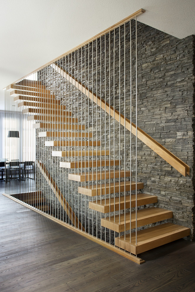Cette image montre un escalier sans contremarche flottant design avec des marches en bois et un garde-corps en matériaux mixtes.
