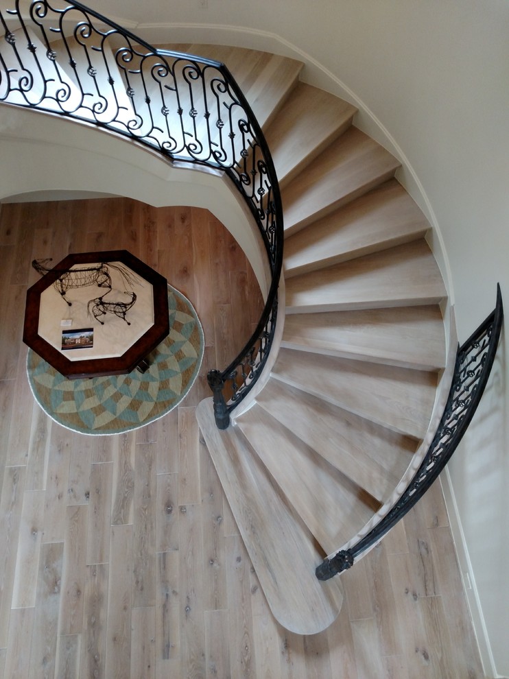 Large mediterranean wood spiral staircase in Houston with wood risers.