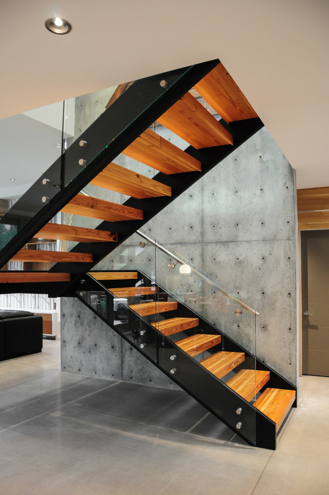 Aménagement d'un grand escalier flottant moderne avec des marches en bois et éclairage.